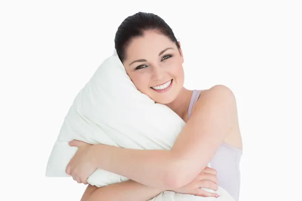 Donna sorridente che tiene un cuscino sullo sfondo bianco — Foto Stock
