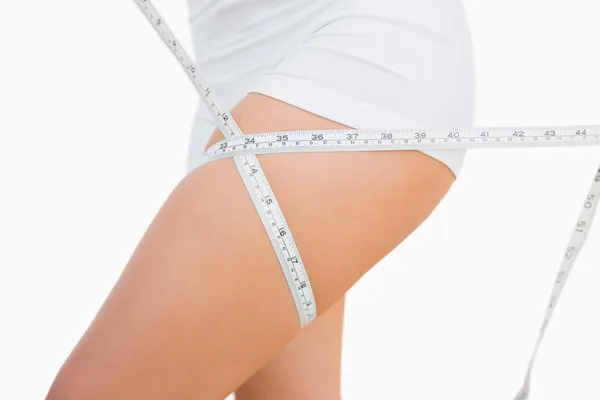 Midsection of fit woman measuring thigh — Stock Photo, Image