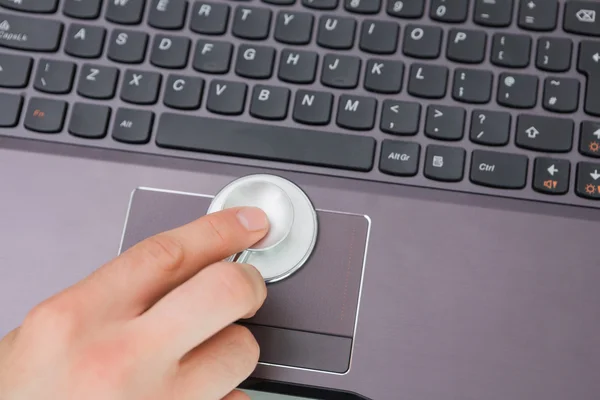 Hand behandeling van touchpad van een laptop met stethoscoop — Stockfoto