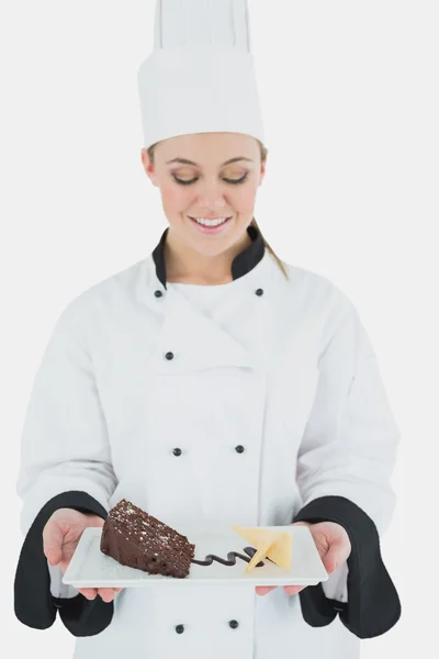 Молодая шеф-повар держит тарелку с кондитерской — стоковое фото