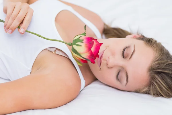 Blonďatá žena leží na posteli s růží — Stock fotografie