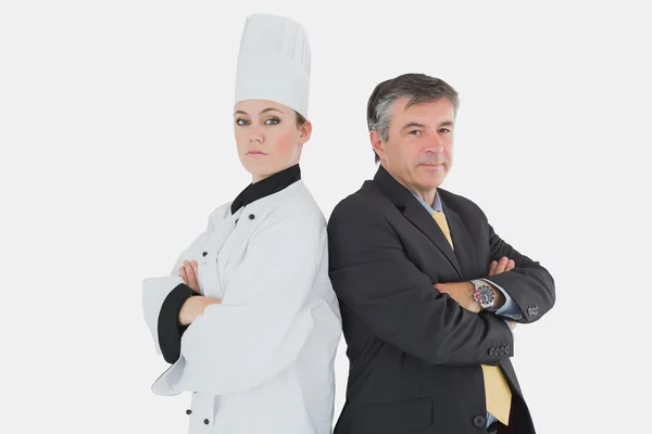 Businessman and chef standing back to back — Stock Photo, Image