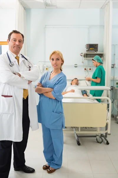 Smiling doctor and nurse standing in a hospital room while foldi — Stock Photo, Image