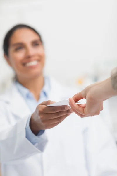 Feliz farmacéutico entregando papel a un cliente — Foto de Stock