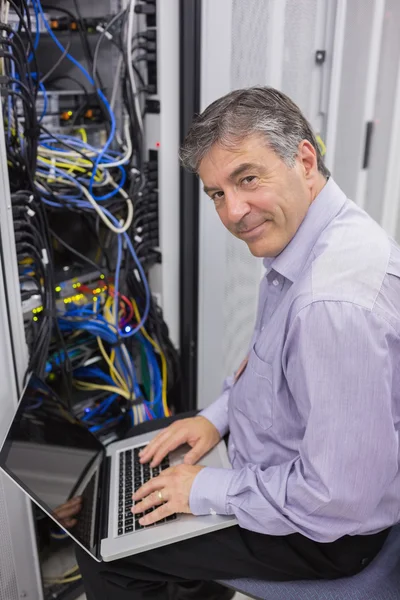 Hombre escribiendo en el ordenador portátil mientras hace mantenimiento del servidor — Foto de Stock