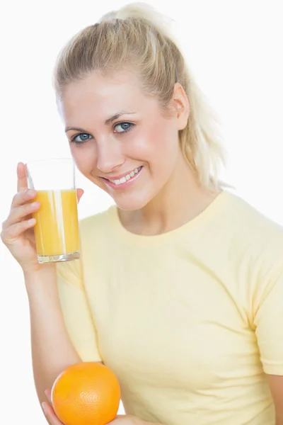 Mulher feliz segurando suco e laranja — Fotografia de Stock