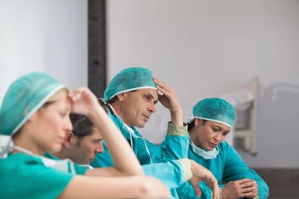 Группа грустных хирургов сидит на полу — стоковое фото