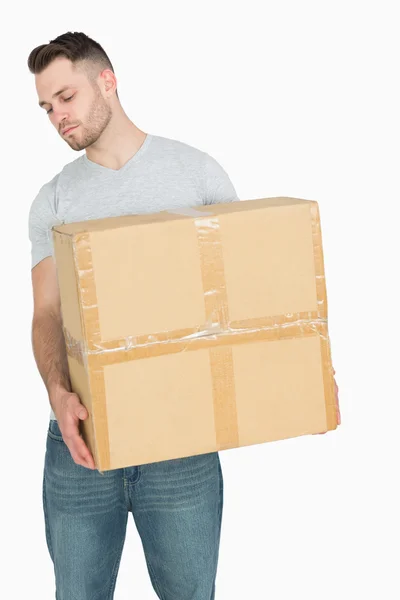 Young casual man carrying cardboard box — Stock Photo, Image