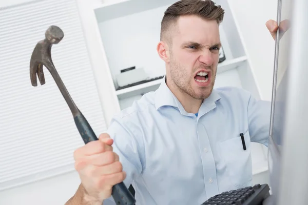 Frustrated man hitting computer monitor with hammer — Stock Photo, Image