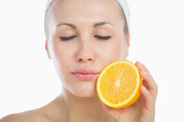 Mujer con los ojos cerrados sosteniendo rebanada naranja — Foto de Stock