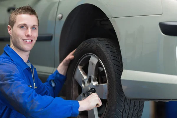 Glücklicher Mechaniker wechselt Autoreifen — Stockfoto