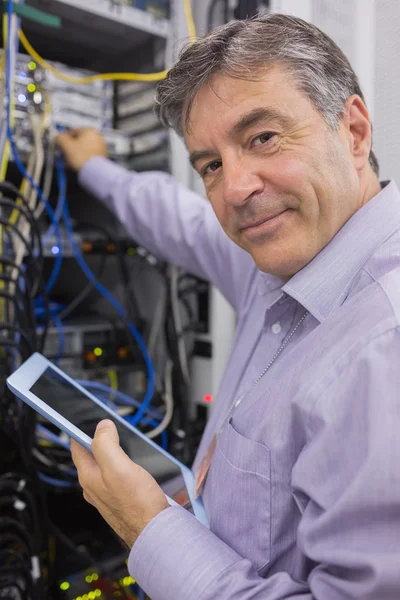 Człowiek uśmiechający się podczas wykonywania konserwacji serwera z tabletem — Zdjęcie stockowe