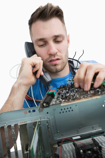 Computer engineer working on sound card on cpu while on call — Stock Photo, Image