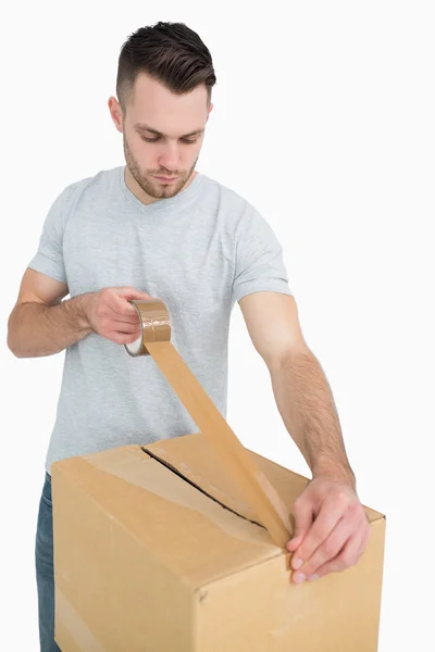 Man verzegeling kartonnen doos met verpakking tape — Stockfoto