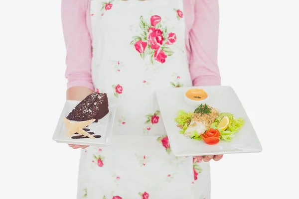 Maid in apron holding plates of pastry and meal — Stock Photo, Image