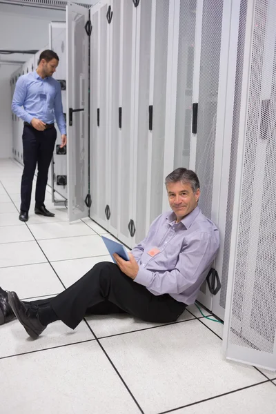 Smiling technician using tablet pc sitting on floor — Stock Photo, Image