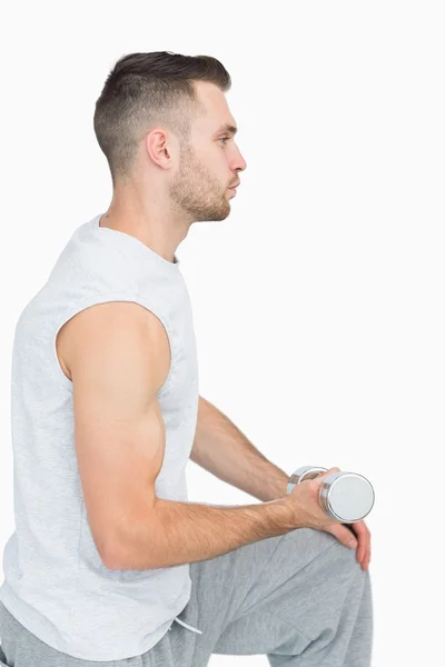 Vista lateral del joven haciendo ejercicio con mancuerna —  Fotos de Stock