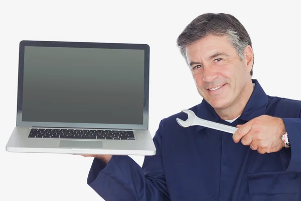 Mature mechanic holding wrench and laptop — Stock Photo, Image