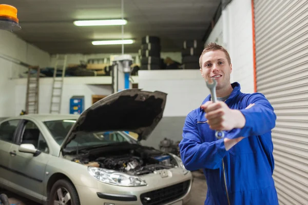 Mechanic offering spanner in worshop — Stock Photo, Image