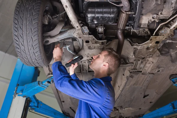 Repairman examining under car — Stock Photo, Image