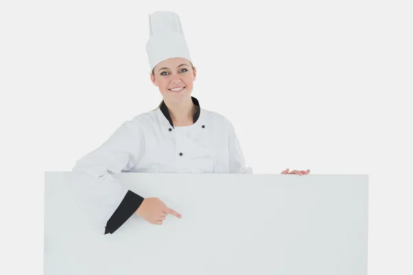 Счастливая шеф-повар, указывающая на рекламный щит — стоковое фото
