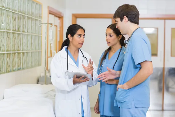 Female doctor talking to a male and a female nurse in a hallway — Stock Photo, Image