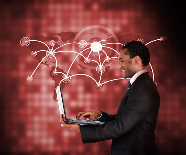 Smiling businessman holding laptop against a background — Stock fotografie