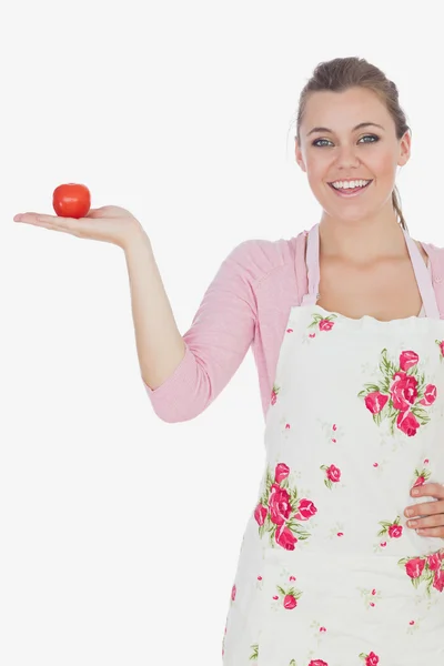 Young woman wearing apron while holding tomato — Stock Photo, Image