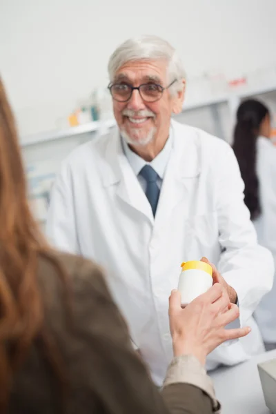 Farmacéutico masculino sonriente apuntando a una caja de pastillas — Foto de Stock