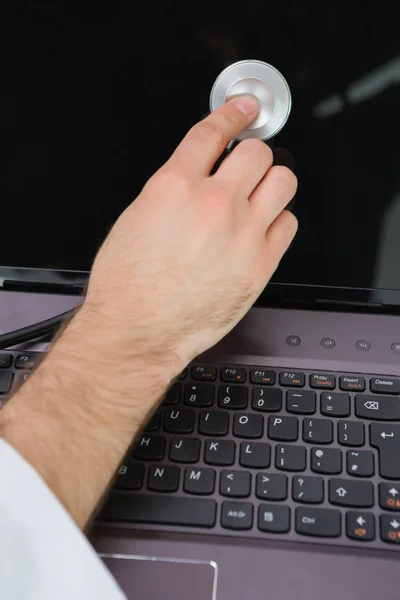 Hand laptop scherm onderzoeken met stethoscoop — Stockfoto