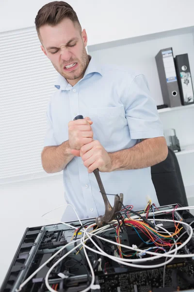 Sinirli adam cpu kablolar çekmek için çekiç kullanarak — Stok fotoğraf