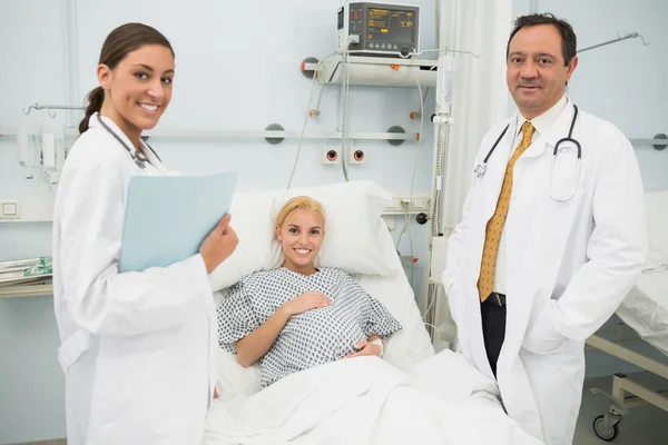 Kvinnliga och manliga läkare står bredvid en kvinnlig patient — Stockfoto