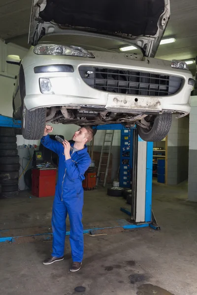 Mechanic working under raised car in garage — Stock Photo, Image