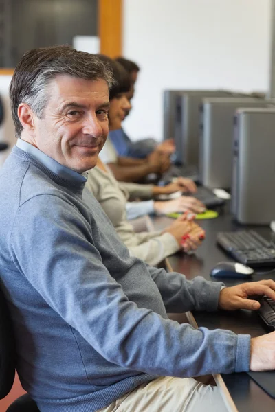 Bilgisayar başında oturan ve gülümseyen bir adam — Stok fotoğraf