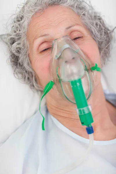 Elderly closing her eyes while lying in a hospital bed — Stock Photo, Image