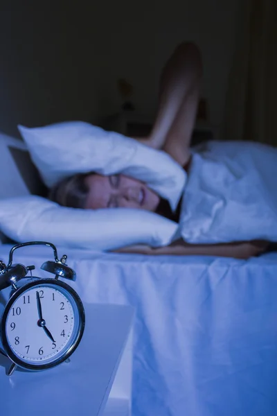 Mujer irritada poniendo almohadas en sus orejas — Foto de Stock