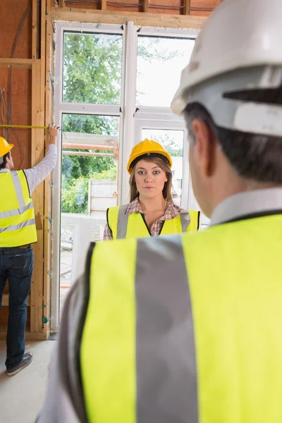 Kobieta szuka zdenerwowany, architekt, podczas gdy człowiek jest pomiar — Zdjęcie stockowe