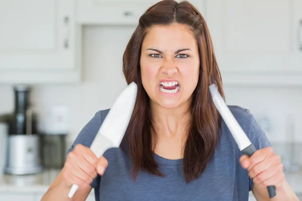 Angry woman holding up knives — Stock Photo, Image