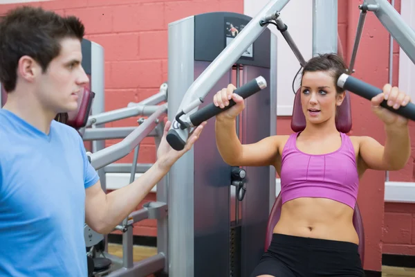 Trainer helpen vrouw op gewichten machine — Stockfoto