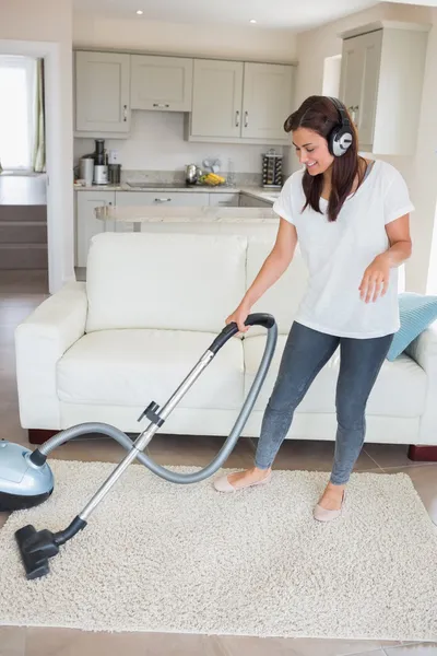 Woman wearing headphones while hoovering — Stock Photo, Image