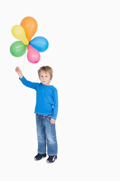 Portrait of young boy holding a bundle of balloons — Stock Photo, Image