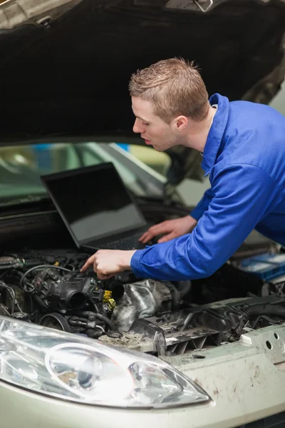 Reparador com laptop verificando o motor do carro — Fotografia de Stock