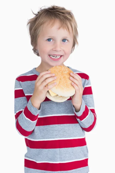 Mignon heureux jeune garçon tenant hamburger — Photo