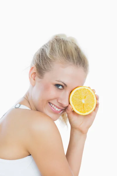 Woman holding slice of orange in front of eye — Stock Photo, Image