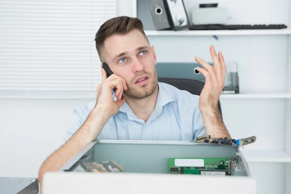 Worried computer engineer on call in front of open cpu — Stock Photo, Image