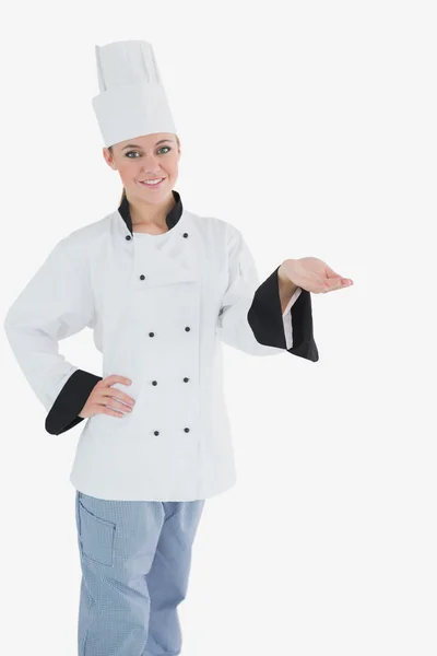 Female chef with hand on waist holding invisible product — Stock Photo, Image