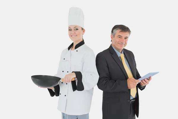 Businessman holding digital tablet and female chef with frying p — Stock Photo, Image