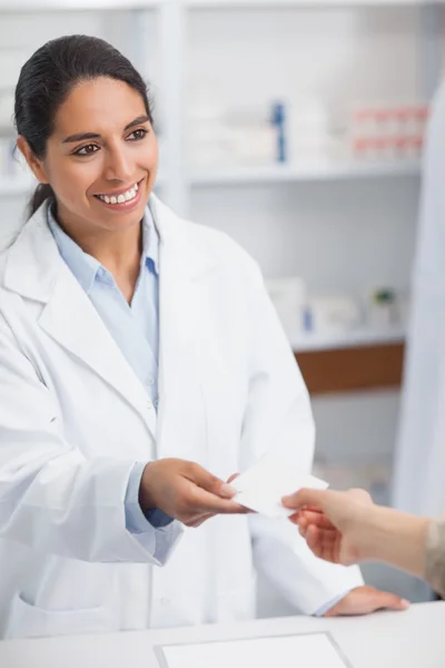 Farmacéutico sonriente entregando papel a un cliente — Foto de Stock