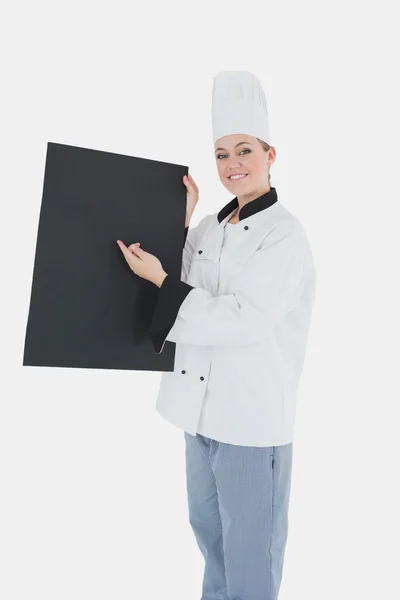 Köchin zeigt auf schwarze Plakatwand — Stockfoto