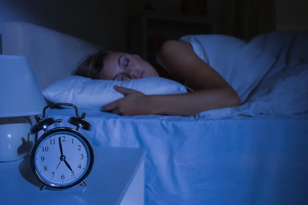 Concentre-se no despertador na frente da mulher adormecida — Fotografia de Stock